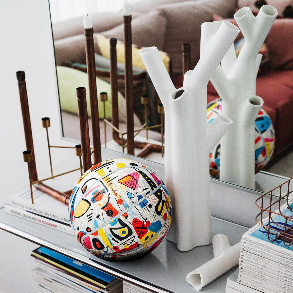 Designbasketbal Pablo op plank tussen woonaccessoires, kleurrijk patroon