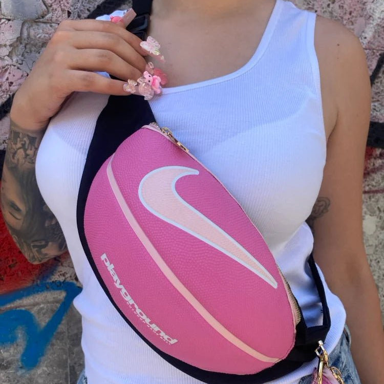 Roze basketbal heuptas crossbody over witte top, met zwarte band en gouden ring