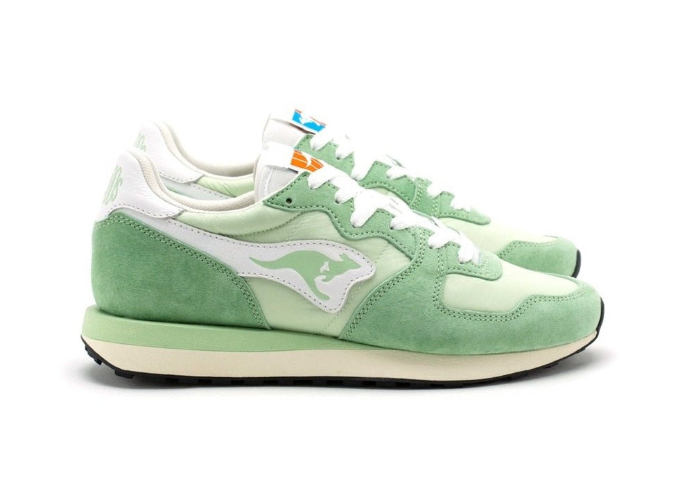 Groene sneakers met witte veters en logo op zijkant, suède-look en witte rand.